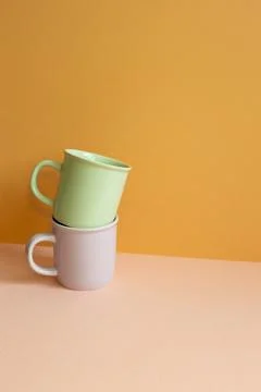 Stack of pastel color mug cup on pink table. orange wall background Stock Photos