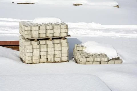 A stack of paving slabs on a construction site covered with snow. Stock Photos