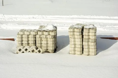 A stack of paving slabs on a construction site covered with snow. Stock Photos