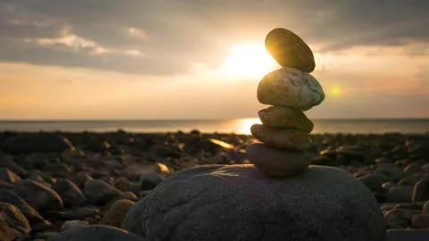 Stack of pebble rocks on a beach at seaside, sunrise Stock Photos