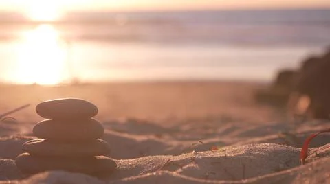 Stack of pebble stones, sandy ocean beach, sunset sky. Rock balancing by water. Foto stock