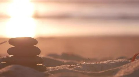 Stack of pebble stones, sandy ocean beach, sunset sky. Rock balancing by water. Foto stock