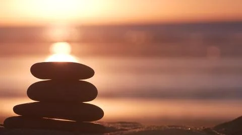 Stack of pebble stones, sandy ocean beach, sunset sky. Rock balancing by water. Foto stock