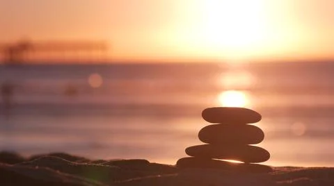 Stack of pebble stones, sandy ocean beach, sunset sky. Rock balancing by water. Foto stock