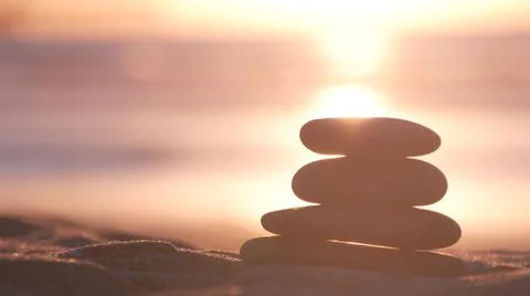 Stack of pebble stones, sandy ocean beach, sunset sky. Rock balancing by water. Foto stock