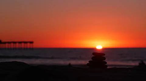 Stack of pebble stones, sandy ocean beach, sunset sky. Rock balancing by water. Foto stock