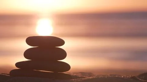 Stack of pebble stones, sandy ocean beach, sunset sky. Rock balancing by water. Foto stock