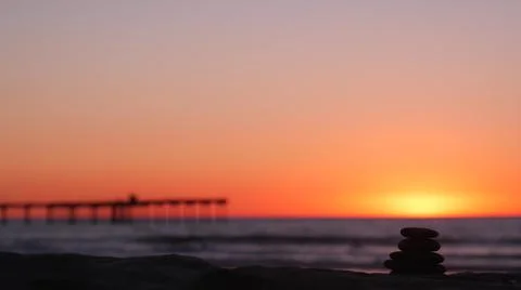 Stack of pebble stones, sandy ocean beach, sunset sky. Rock balancing by water. Foto stock