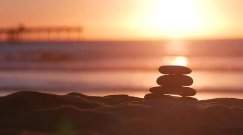 Stack of pebble stones, sandy ocean beach, sunset sky. Rock balancing by water. Foto stock