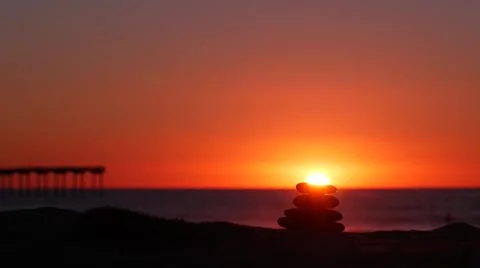Stack of pebble stones, sandy ocean beach, sunset sky. Rock balancing by water. Foto stock