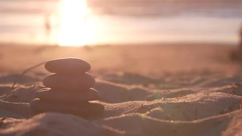 Stack of pebble stones, sandy ocean beach, sunset sky. Rock balancing by water. Foto stock