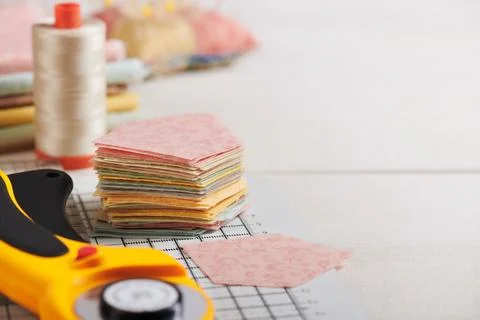 Stack of pentagon pieces of fabrics on white craft mat, sewing accessories Stock-Fotos
