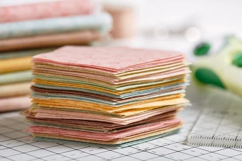 Stack of pentagon pieces of fabrics on white craft mat 스톡 사진