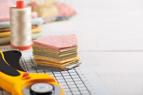 Stack of pentagon pieces of fabrics on white craft mat, sewing accessories Stock Photos