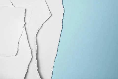 Stack of pieces of ripped and torn white paper on a blue background. Copy spa Stock Photos