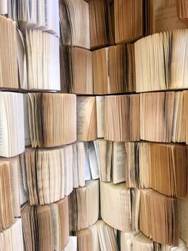 Stack pile of opened old books collection attached to the wall with pages out Stock Photos