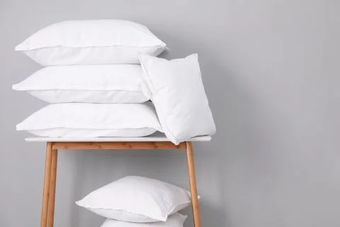 Stack of pillows on bench against grey wall. Space for text Stockfoto's