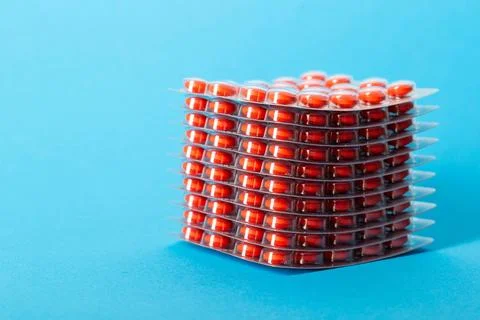 Stack of pills blisters with red pills on blue background. Concept of rifamycin Foto stock