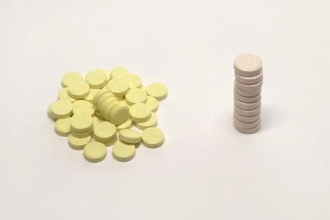 Stack of pills with inclusions and heap of yellow tablets with parting lines Stock Photos