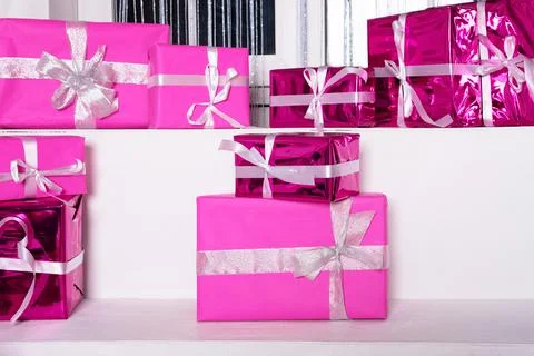 Stack of pink celebration gift boxes with ribbon bows on white table. Winter  Stock Photos
