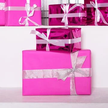 Stack of pink celebration gift boxes with ribbon bows on white table. Winter  Foto stock