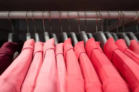 Stack of pink color shade polo cotton t-shirts clothing with hanging in closet Stock Photos
