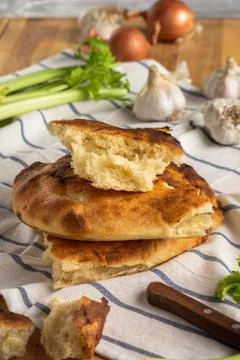 A stack of pita bread on a striped towel, garlic, onion and celery Stock-Fotos