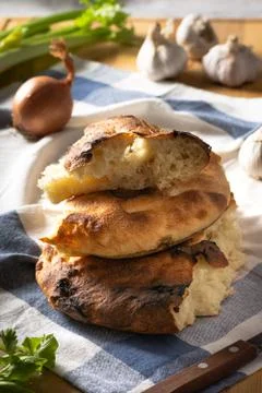 A stack of pita bread on a striped towel, garlic, onion and celery Stock Photos