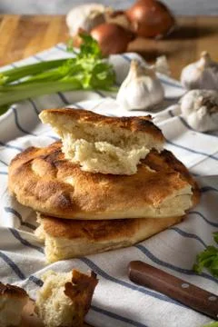 A stack of pita bread on a striped towel, garlic, onion and celery Stock Photos