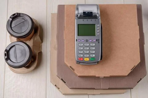 Stack of pizza boxes, cups of coffee and terminal Stock Photos