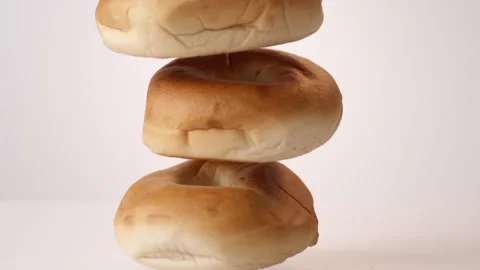 Stack of plain bagels bouncing on white slow motion macro food studio 4K stock Stock Footage 336706657