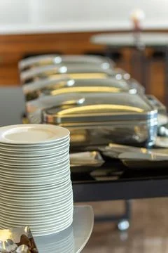 Stack of plates next to closed chafing dishes Stock Photos