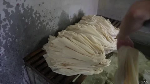 Stack of pleated undyed cotton cloth resting on a wooden rack above a rinsing Stock Footage 342319556
