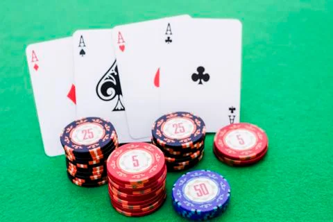 Stack of poker chips and four cards with aces on green background Stock Photos