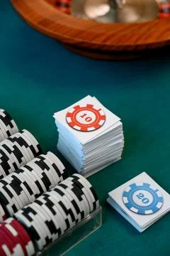 Stack of poker chips and playing cards on green casino table Stock Photos