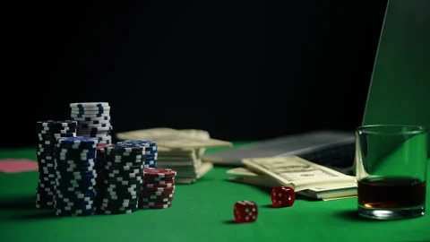 Stack of poker chips, dice, and money on table beside laptop, online casino 動画素材 312329590