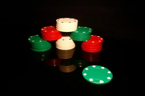 Stack of poker chips with a green chip in front and reflections isolated on b Stock Photos