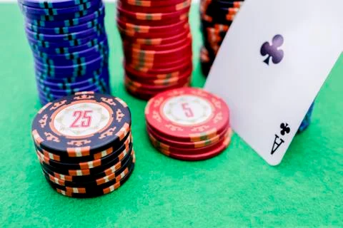 Stack of poker chips next to a card with an ace on a green game table Stock Photos
