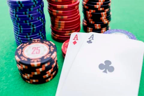 Stack of poker chips next to two cards with aces on a green game table Stock Photos