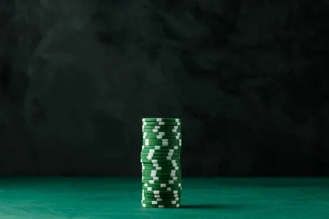 Stack of poker green chips on the table on a black background Stock Photos