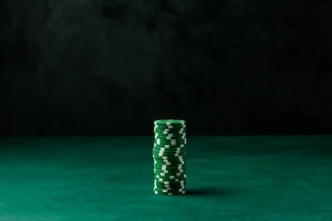Stack of poker green chips on the table on a black background Stock Photos