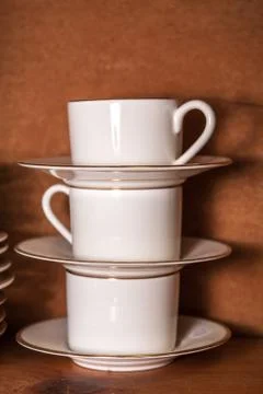 Stack of porcelain coffee cups with gold rim on wooden background Stock Photos