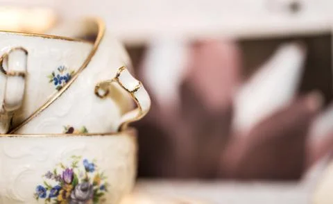 Stack of porcelain coffee cups with gold rim and floral design on white pink  Foto stock