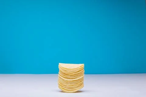 Stack of potato chips on table against blue background with copy space Stock Photos