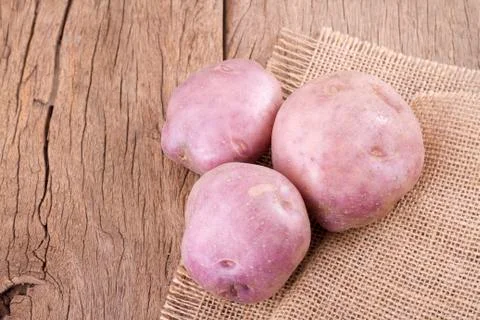 Stack of potatoes on wooden table (Solanum tuberosum) Stock Photos