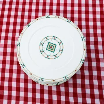 Stack of pristine, beautiful plates arranged a checkered tablecloth, showcasi Stock Photos