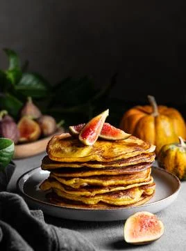Stack of pumpkin and pancakes with honey and figs on a dark background with.. 스톡 사진