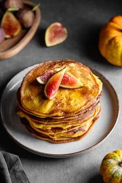 Stack of pumpkin and pancakes with honey and figs on a dark background with.. 스톡 사진