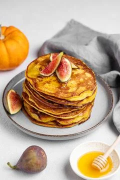 Stack of pumpkin pancakes with honey and figs in a plate on light backgroun.. Stock Photos
