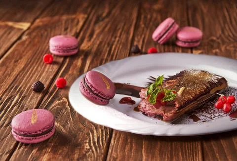 Stack of purple macarons with chocolate and berries on wooden table Stock Photos